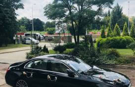 zdjęcie czarnego Mercedesa na podjeździe przystrojonego do ślubu